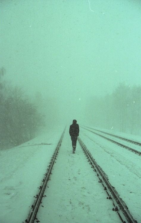 a person walking on train tracks in the snow