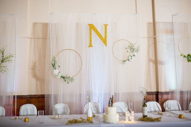 the table is set up with white linens and greenery, along with two cakes