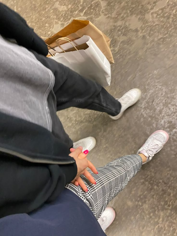 two people sitting next to each other with their feet up in the air and one person holding a paper bag