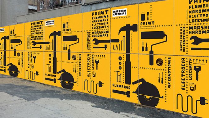 a large yellow sign with various tools on it's side next to a building