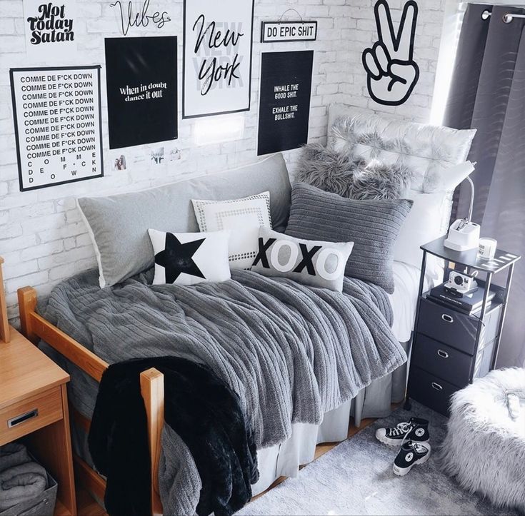 a bedroom with white brick walls and grey bedding, black and white pillows, and pictures on the wall