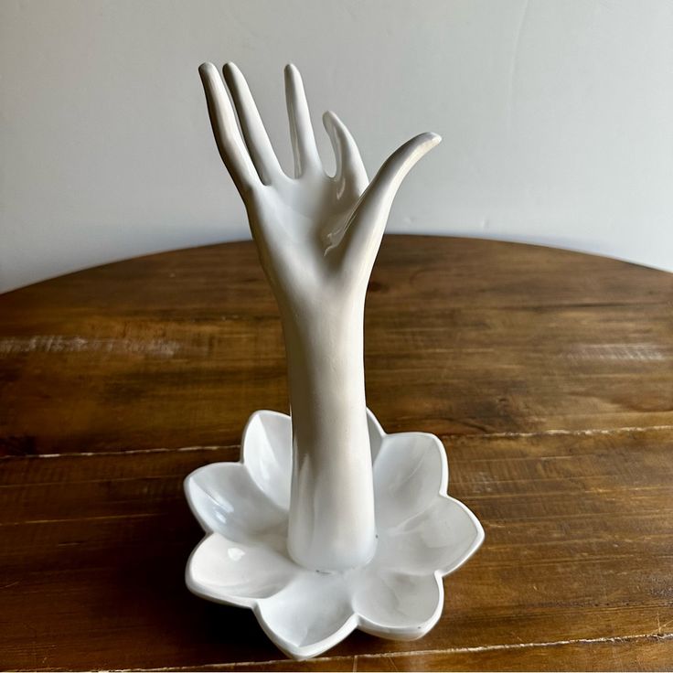 a white hand statue sitting on top of a wooden table