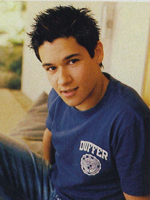 a young man sitting on the floor wearing a blue shirt