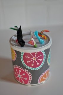 two small birds are perched on top of a tin can with some fabric in it