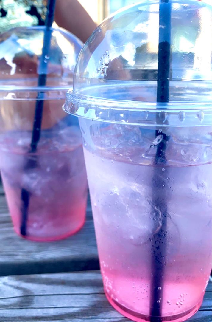 two plastic cups filled with liquid on top of a wooden table