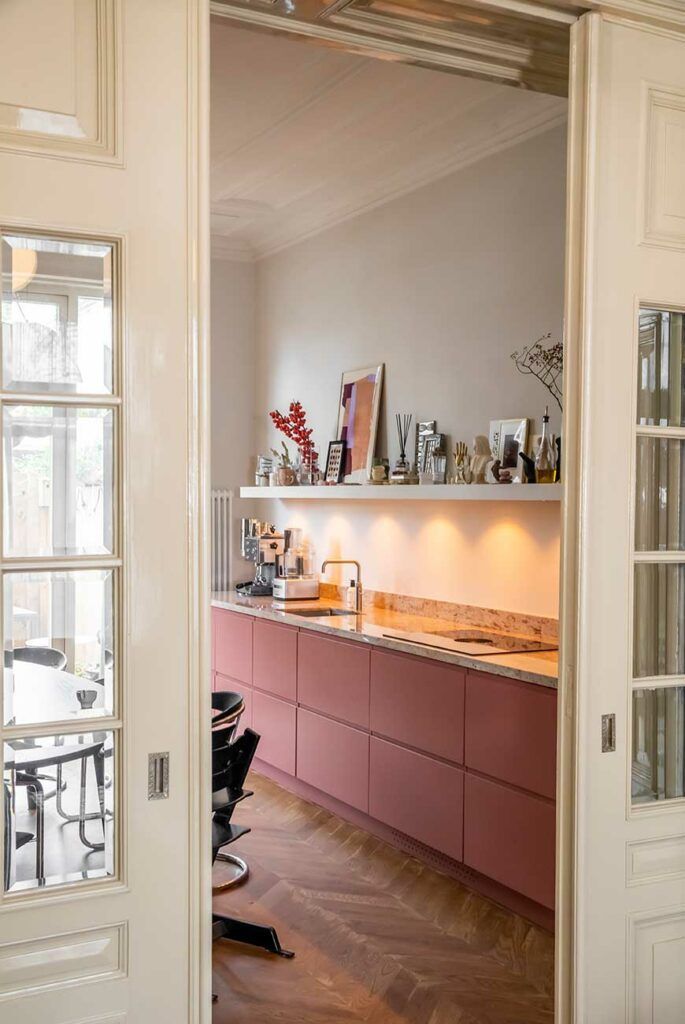 an open door leading to a kitchen with pink cabinets and counter tops on the wall