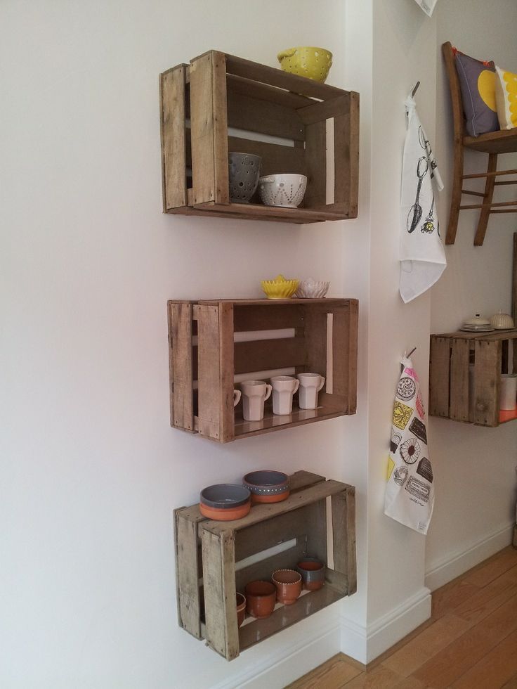 three wooden crates are stacked on the wall next to each other, with dishes in them