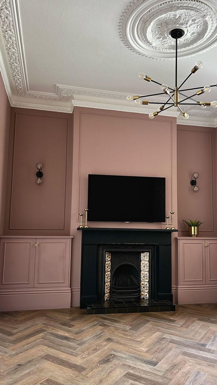 a living room with pink walls and wood flooring, a tv mounted on the wall