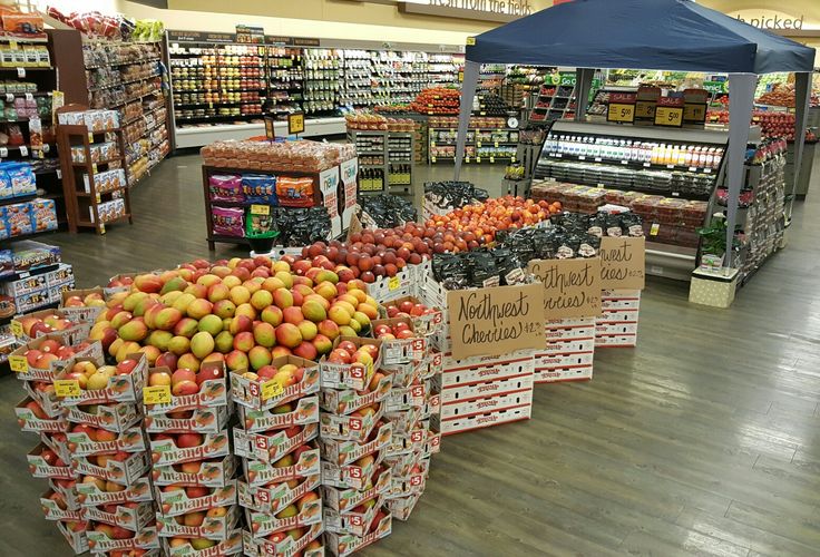 the produce section of a grocery store with apples and oranges on display for sale