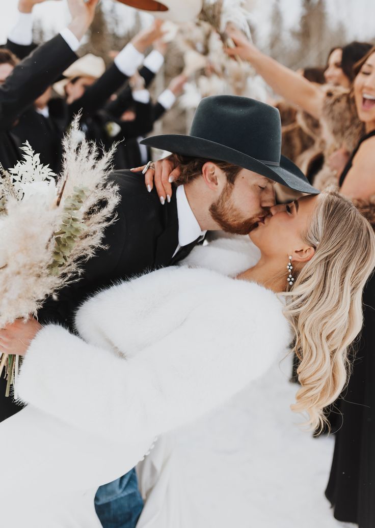 a bride and groom kissing in front of their wedding party