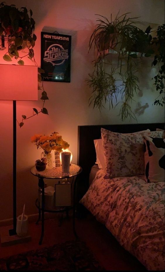 there is a bed with flowers and candles on the night stand in front of it