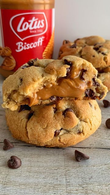 two cookies with peanut butter and chocolate chips next to a jar of biscoff