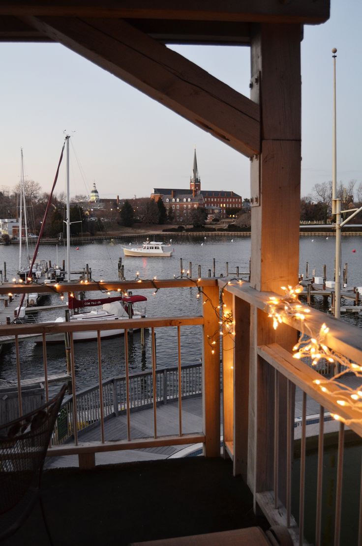 a balcony with lights on the railing and boats in the water