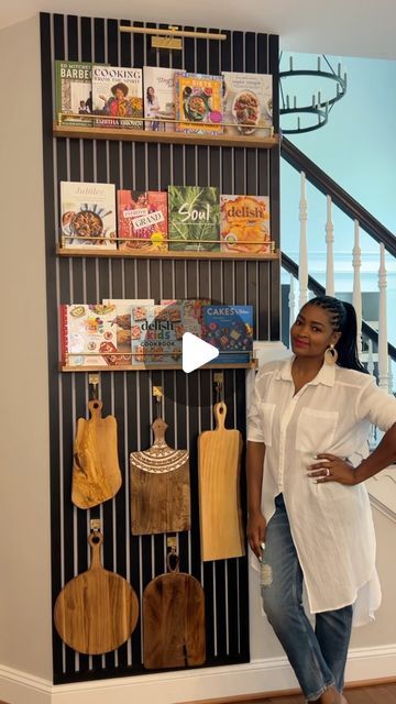 a woman standing in front of a wall with books and purses hanging on it