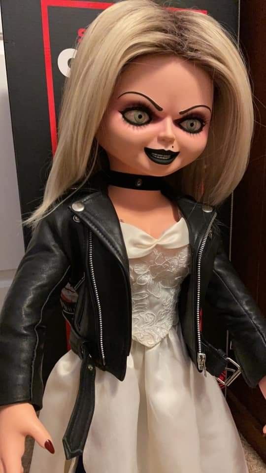 a doll dressed in a white dress and black leather jacket is posed for the camera