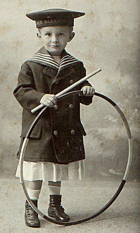 an old black and white photo of a young boy holding a hoop