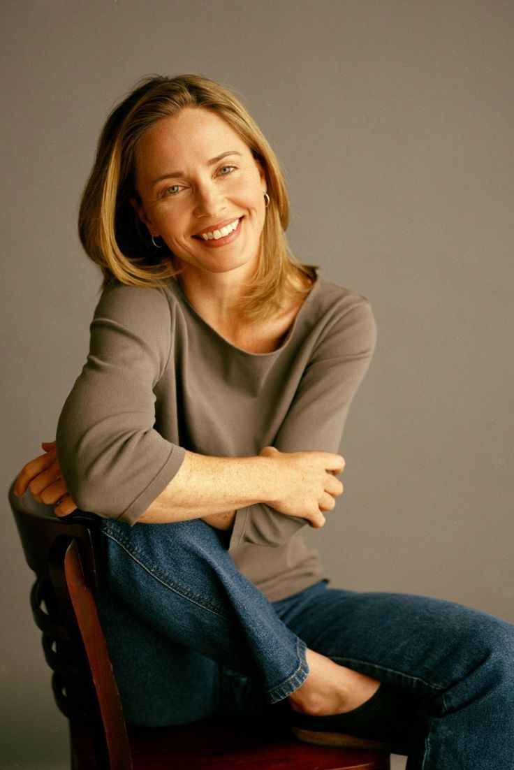 a woman sitting on top of a wooden chair with her arms crossed and legs crossed