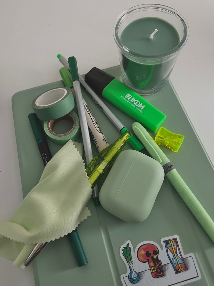 a green tray topped with lots of different items next to a cup filled with liquid