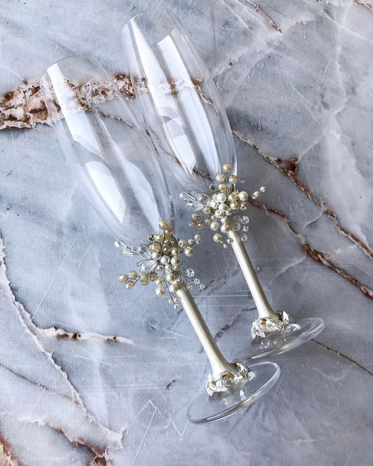 two champagne flutes with flowers on them sitting on a marble surface