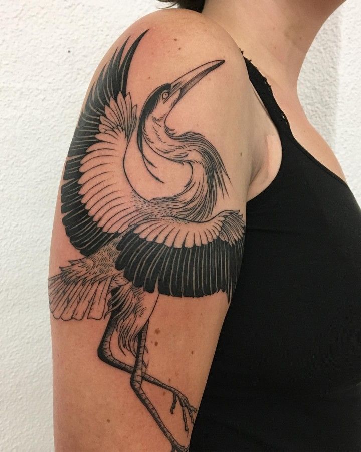 a woman with a black and white tattoo on her arm holding a bird in its beak