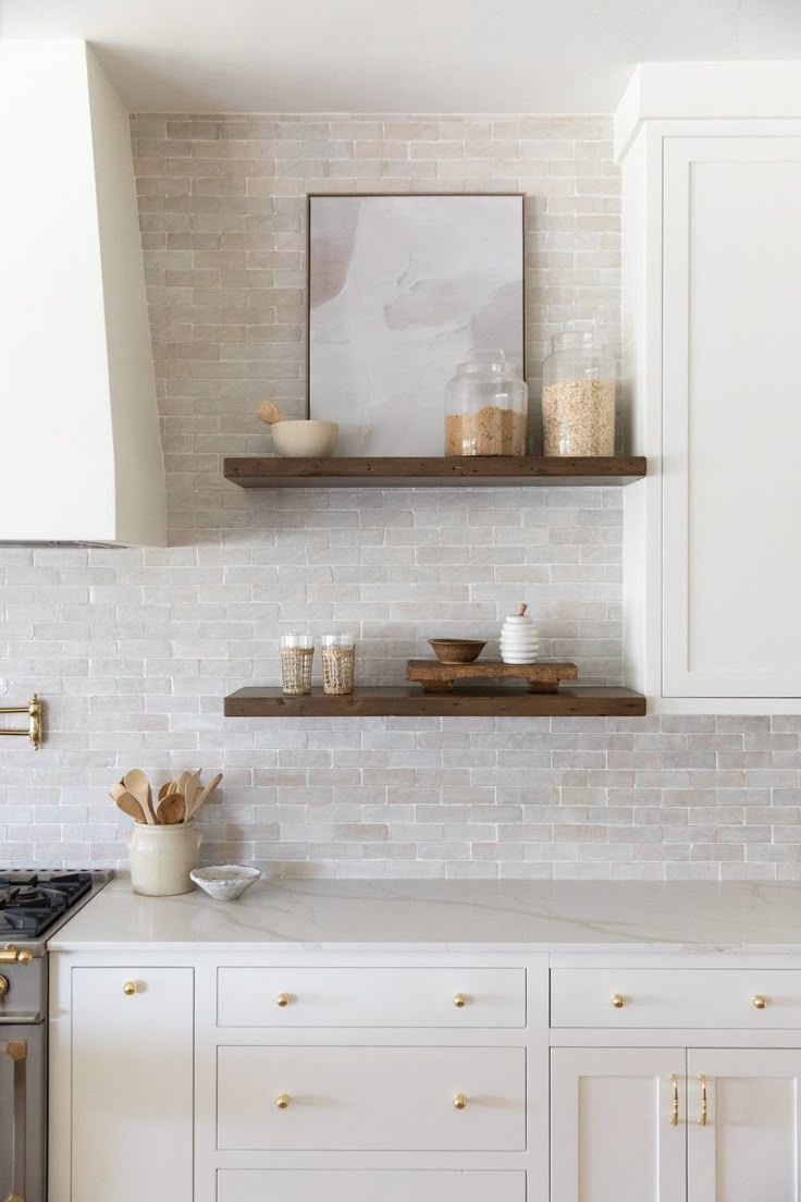 a kitchen with white cabinets and gold handles