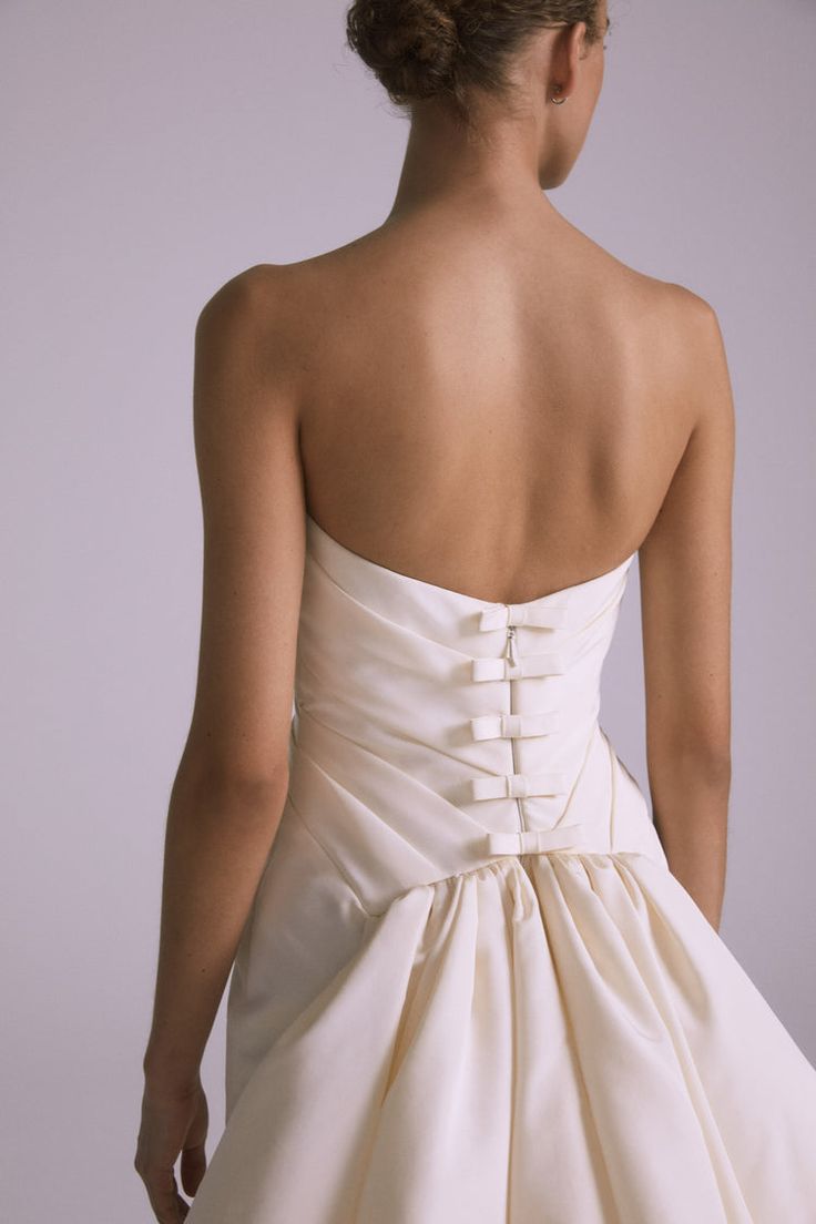 the back of a woman's wedding dress, with her hand on her hip