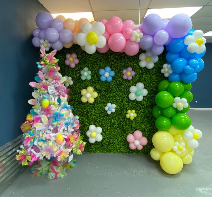 a room decorated with balloons, flowers and a fake grass wall in the shape of a house