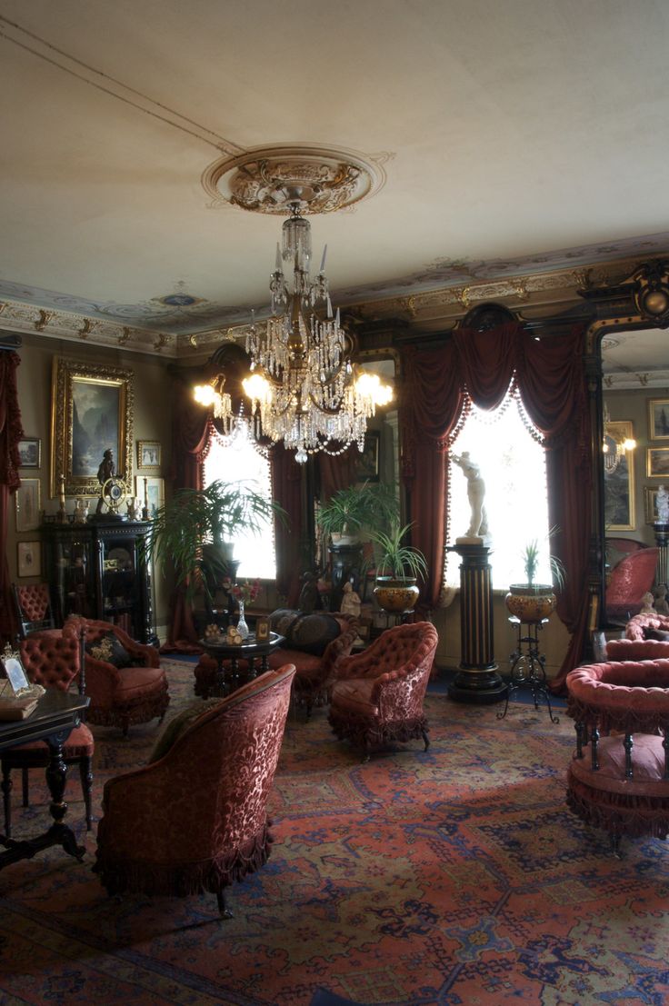 a living room filled with lots of furniture and a chandelier hanging from the ceiling