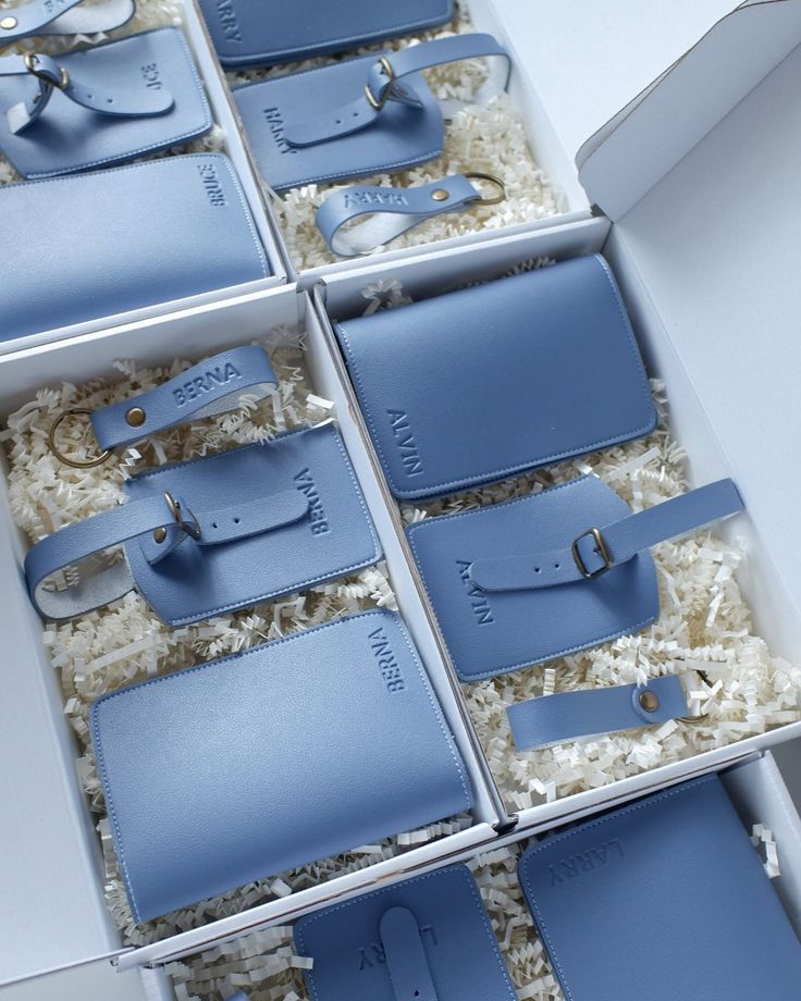 six blue purses in a white box on top of a carpeted floor, with one opened and the other closed