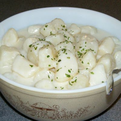 a white bowl filled with dumplings and garnished with green sprinkles