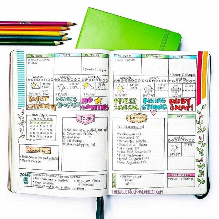 an open planner book sitting on top of a table next to colored pencils and markers