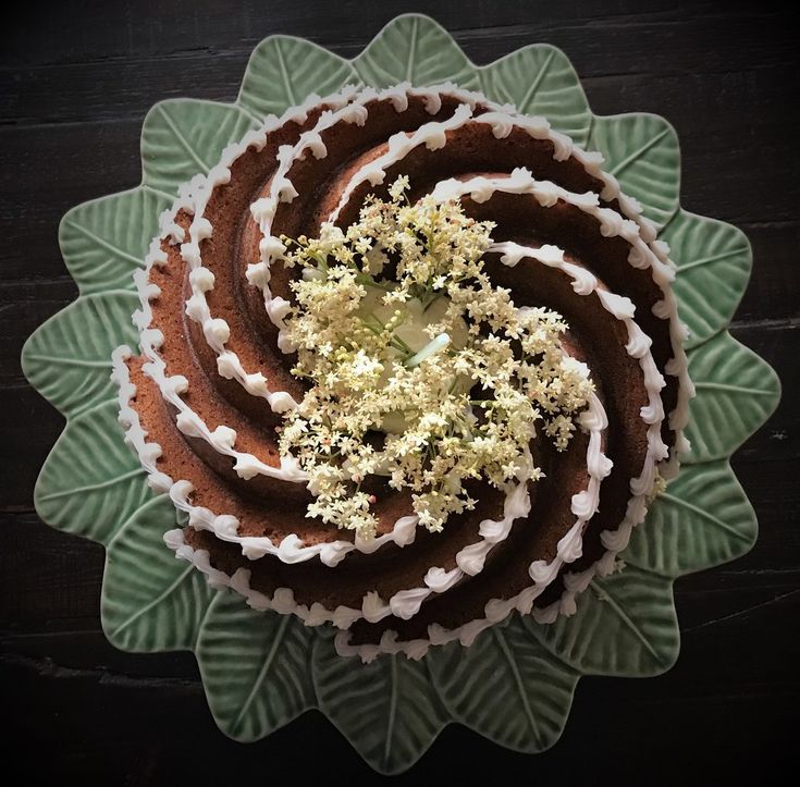 there is a cake with white flowers on the top and green leaves in the middle