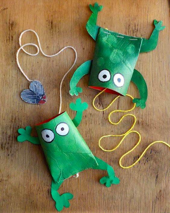 two green paper bags with googly eyes and one has a string attached to it