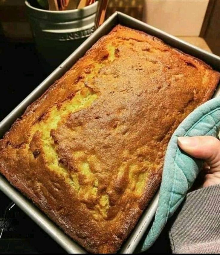 a person holding a loaf of bread in a pan