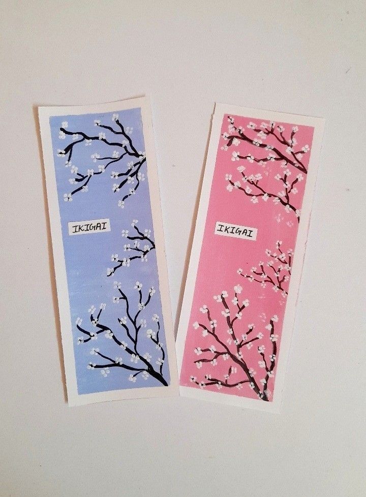 two bookmarks with trees on them sitting next to each other in front of a white wall