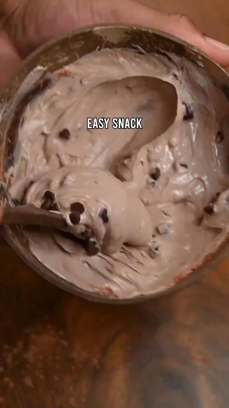 a person holding a spoon full of ice cream with chocolate chips on it and the words easy snack in front of them