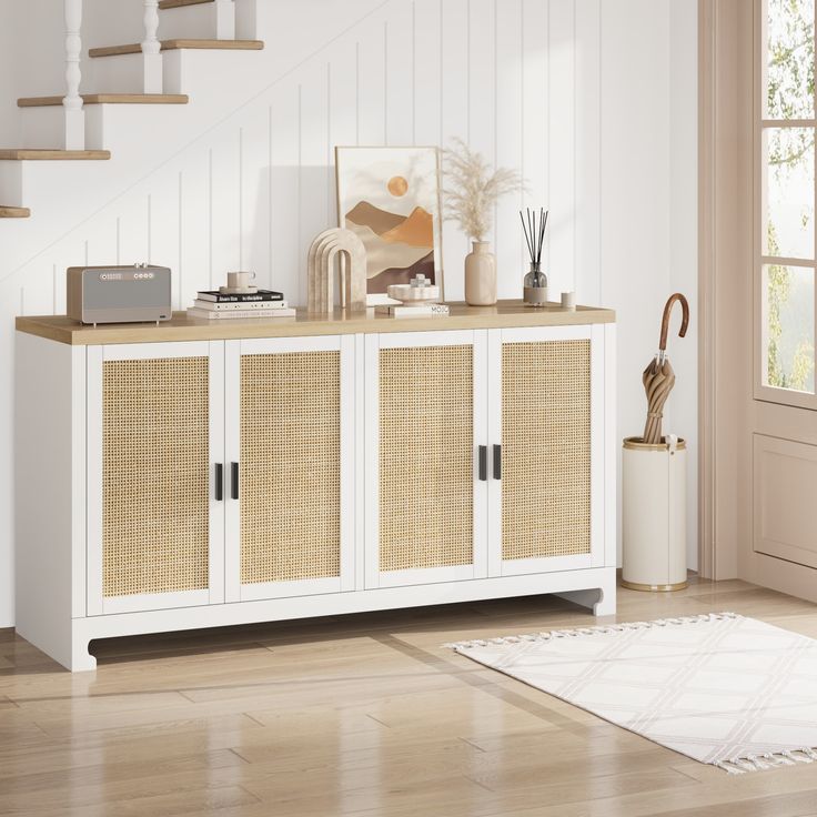 a white cabinet with wicker doors and drawers in a living room next to stairs