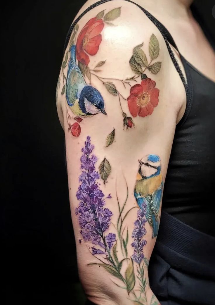 a woman's arm with flowers, birds and leaves on the left side of her body