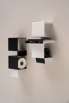 some black and white items are hanging on the wall next to a toilet paper dispenser