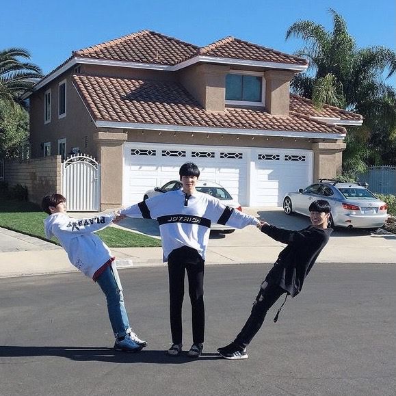 three young men standing in the middle of a street with their arms around each other