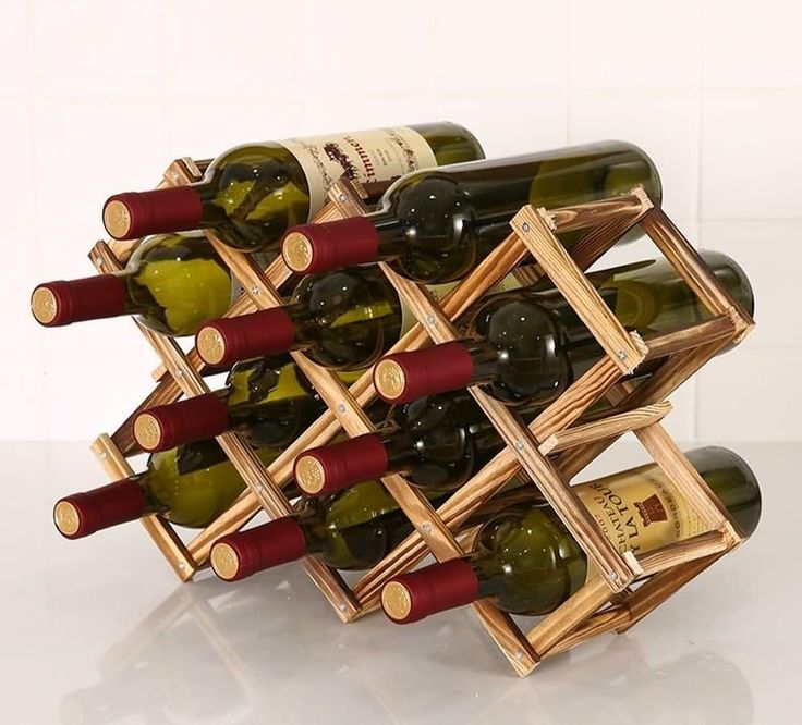 a bunch of wine bottles that are in a wooden holder on a table top with white tiles behind them