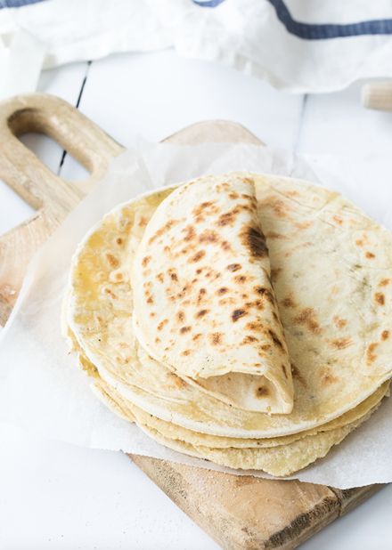 three tortillas sitting on top of a wooden cutting board