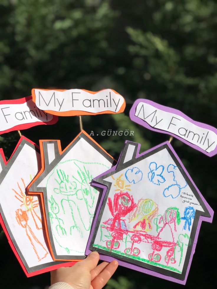 a hand holding up some paper houses with writing on them that read, i love my family