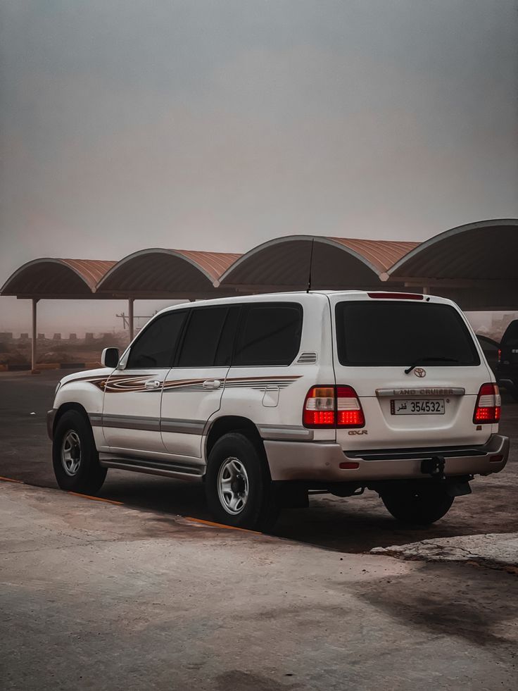 a white suv parked in front of a parking lot with umbrellas on the roof