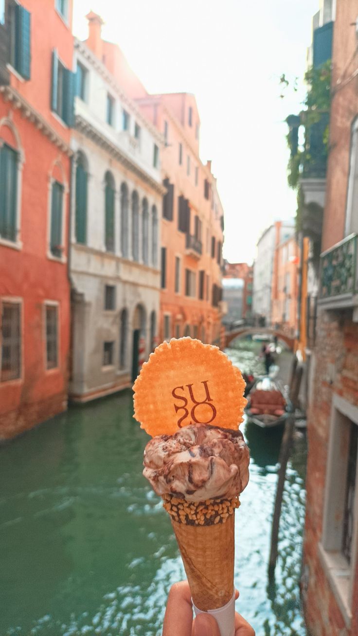 someone holding up an ice cream cone with the number 30 on it in front of a canal