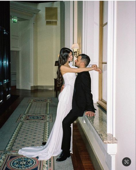 a bride and groom standing next to each other in front of a window sill