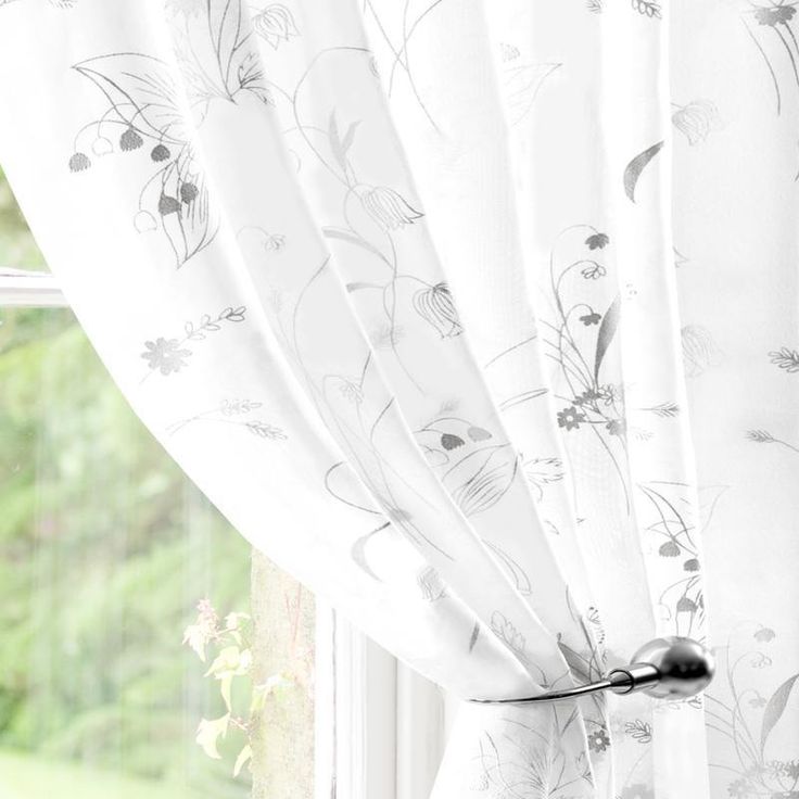 a window with white curtains and flowers on it