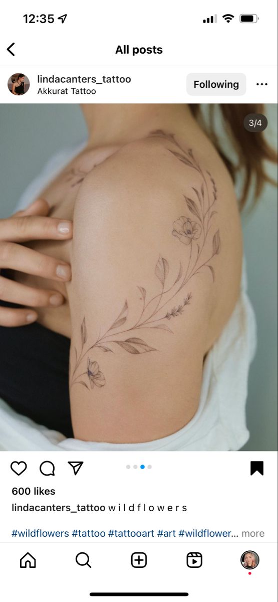 the back of a woman's stomach with flowers on it and an arrow tattoo