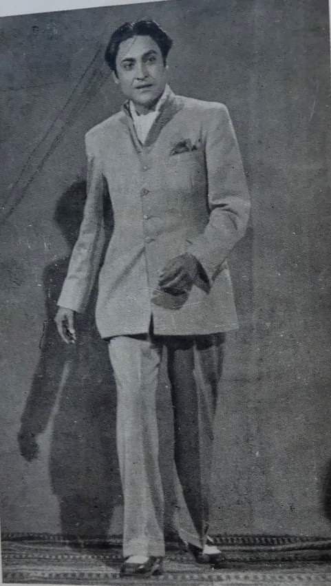 an old black and white photo of a man in a suit standing with his hands in his pockets