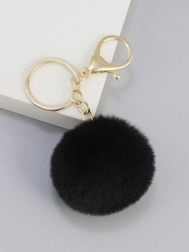 a black fur ball keychain hanging on a white surface